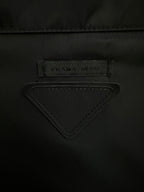 Triangular PRADA logo label on black jacket fabric