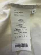 Cotton T-shirt care label on cream fabric, size M, 100% cotton