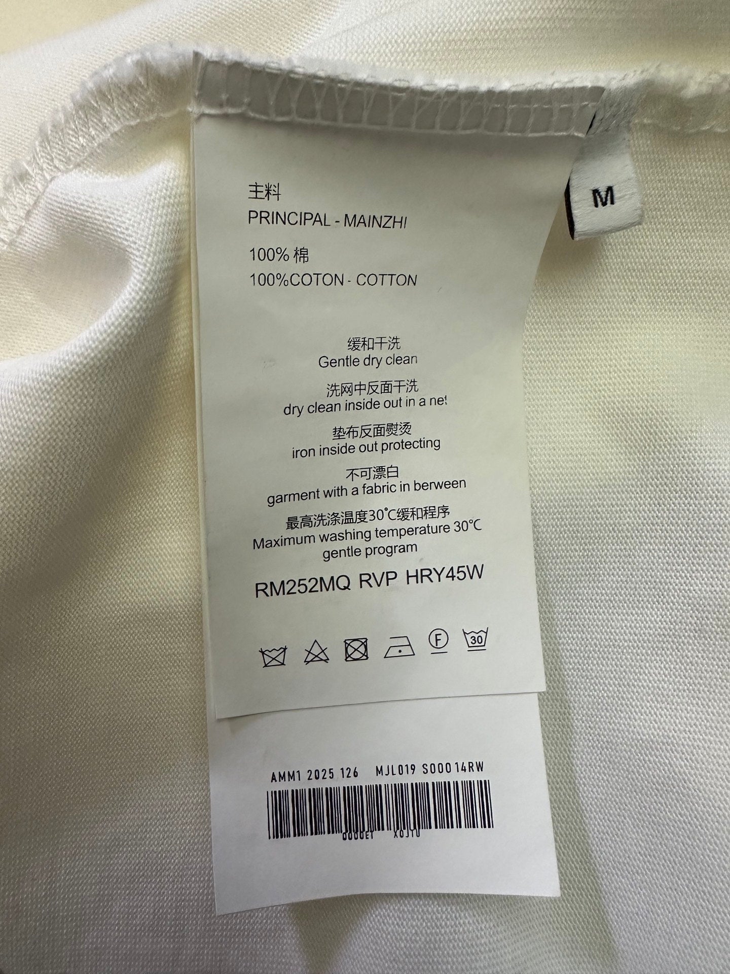 Cotton T-shirt care label on cream fabric, size M, 100% cotton