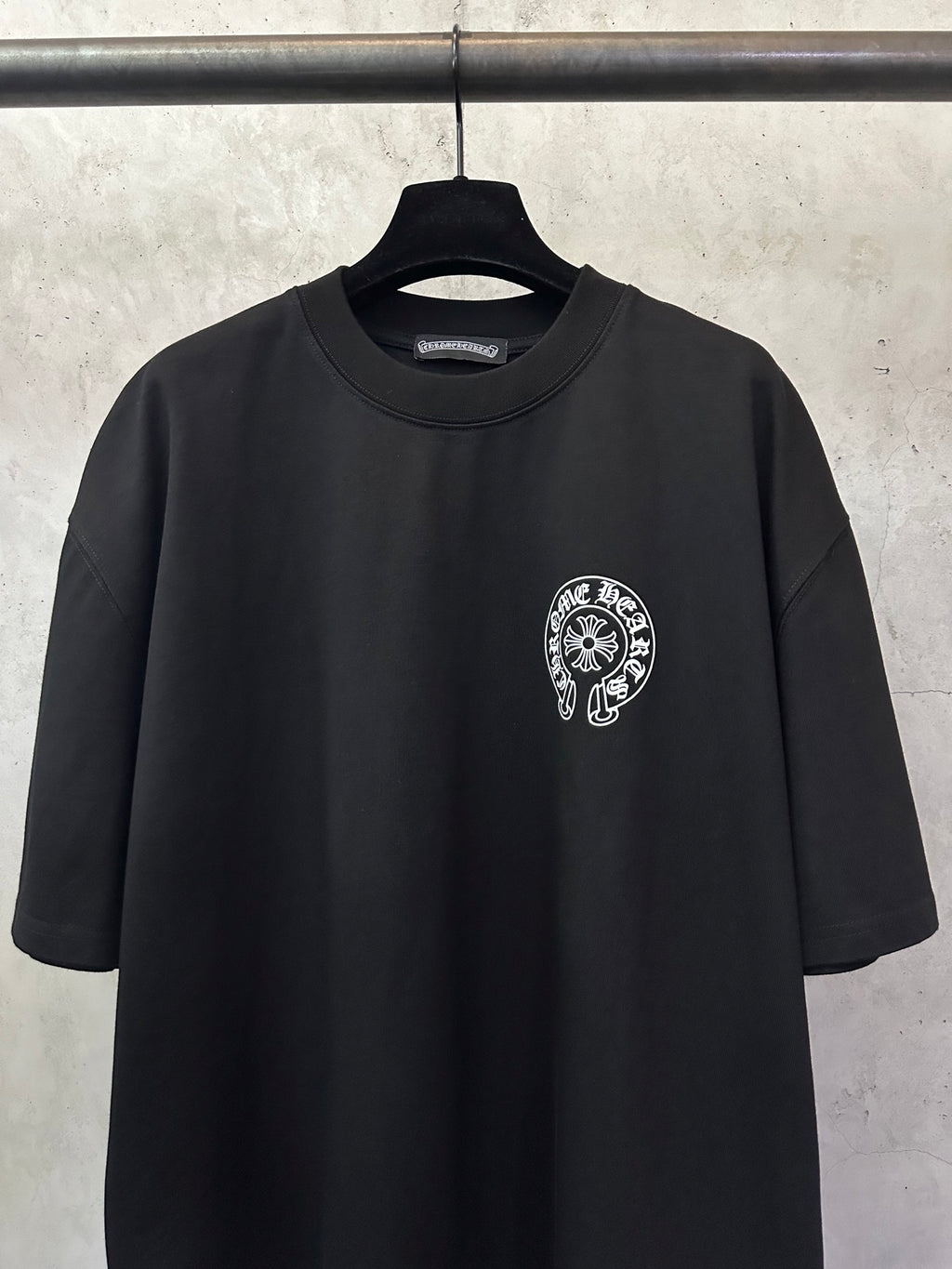 Black short-sleeve T-shirt with circular chest logo patch at center