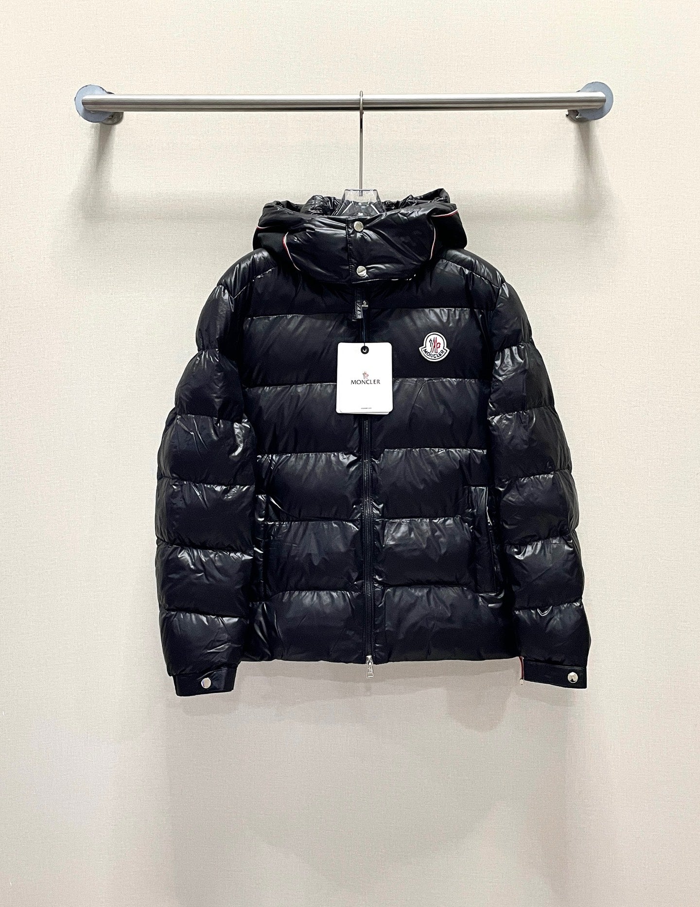 Moncler long puffer jacket, dark color front view with hood, on hanger