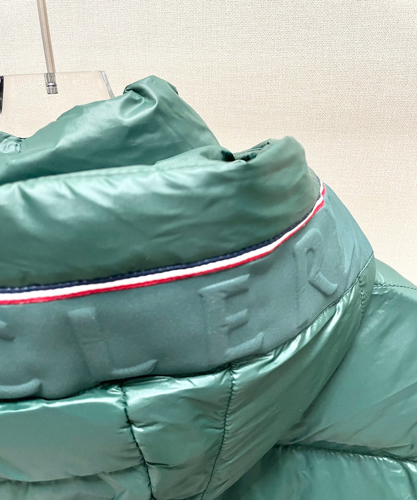 Dark green puffer jacket hood edge with red-and-blue trim detail