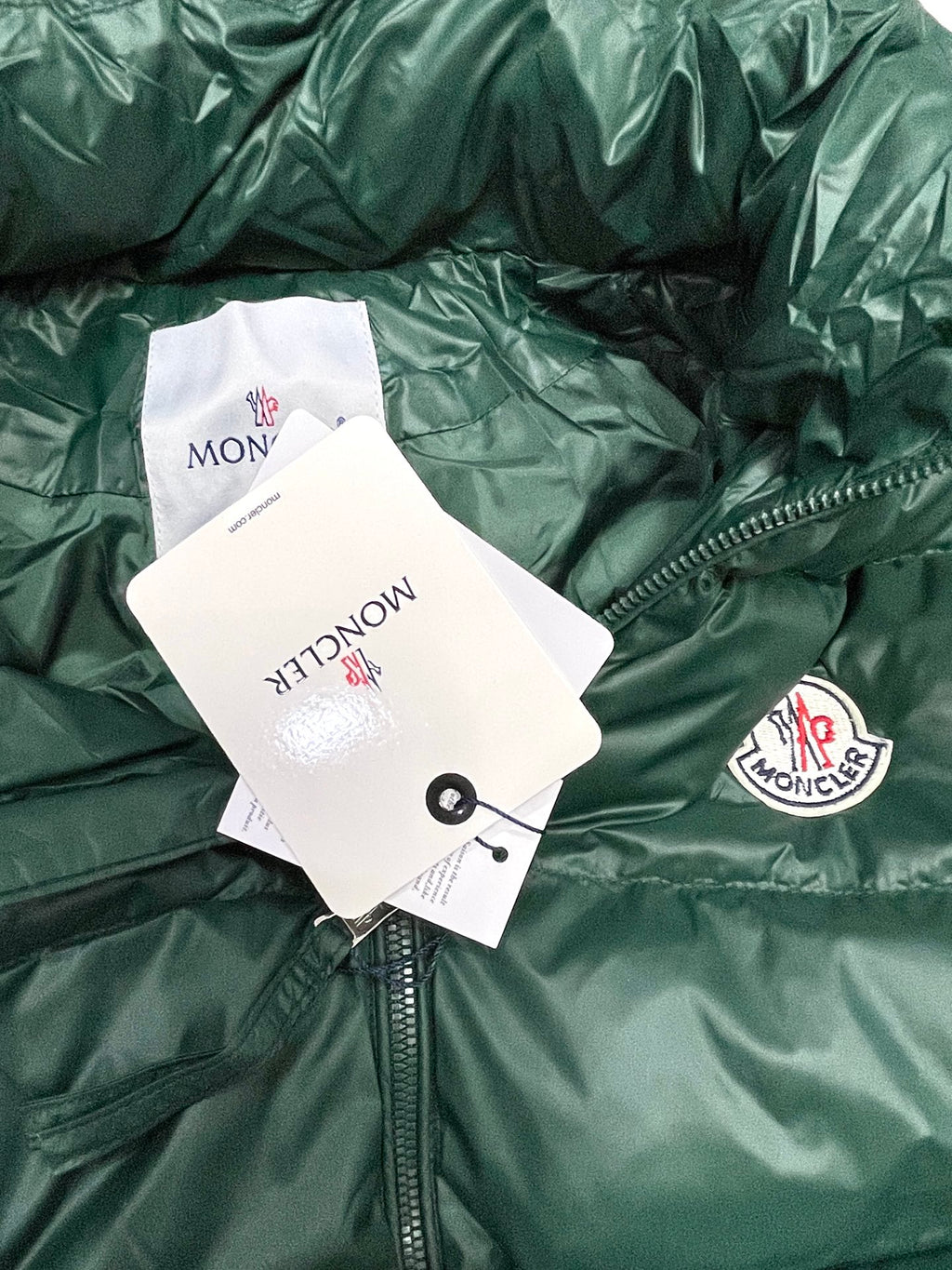 Green Moncler puffer jacket fabric close-up with hanging product tags