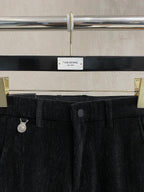 Black trousers waistband with belt loops, button, and coin charm detail