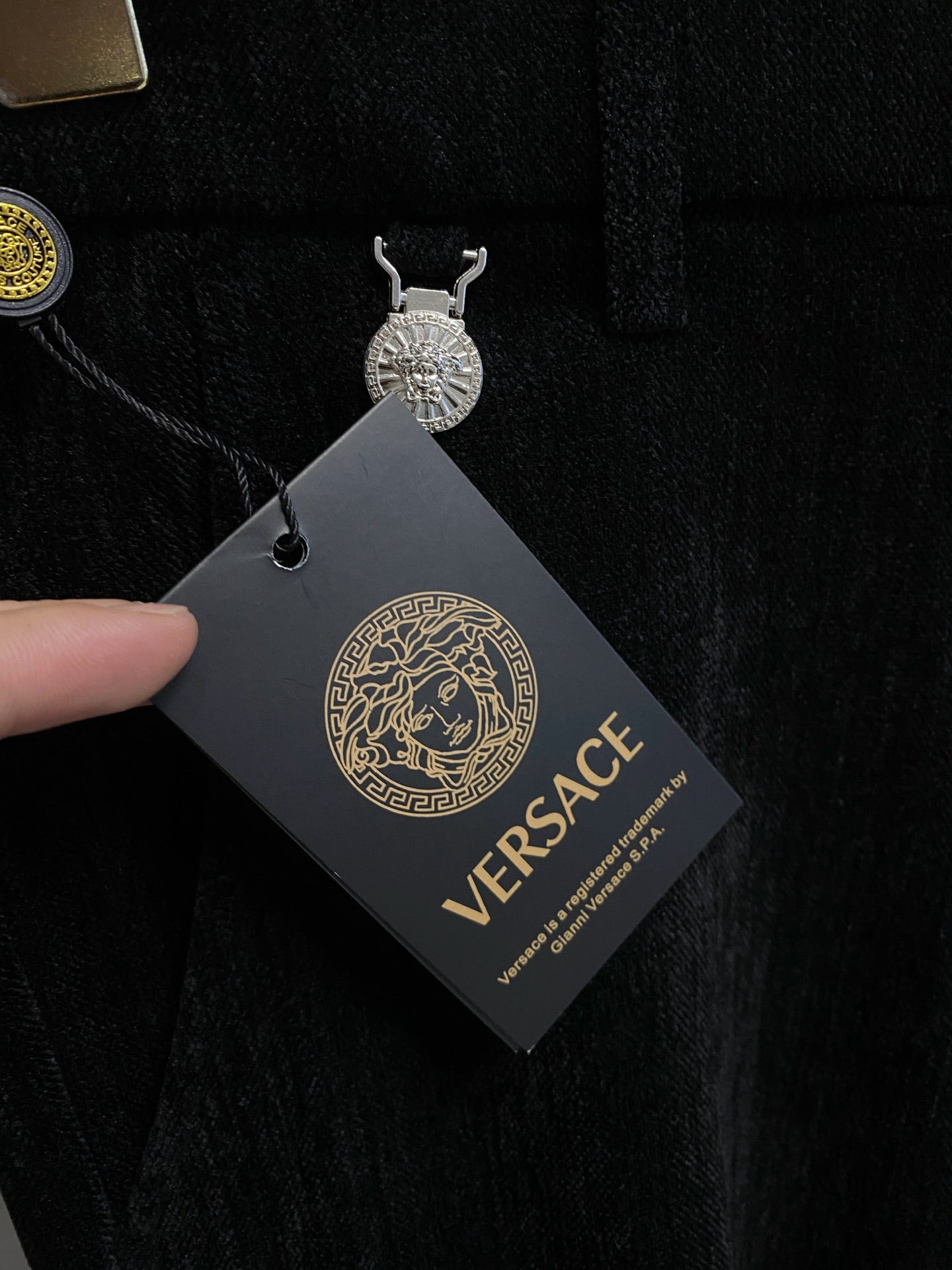 Black Versace trousers with attached hang tag showing logo