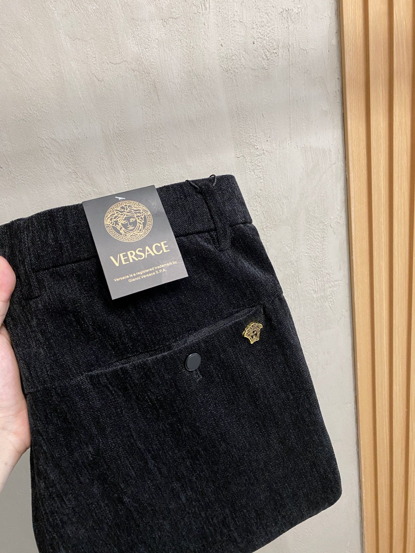 Black Versace trousers with waistband logo label and gold crest button