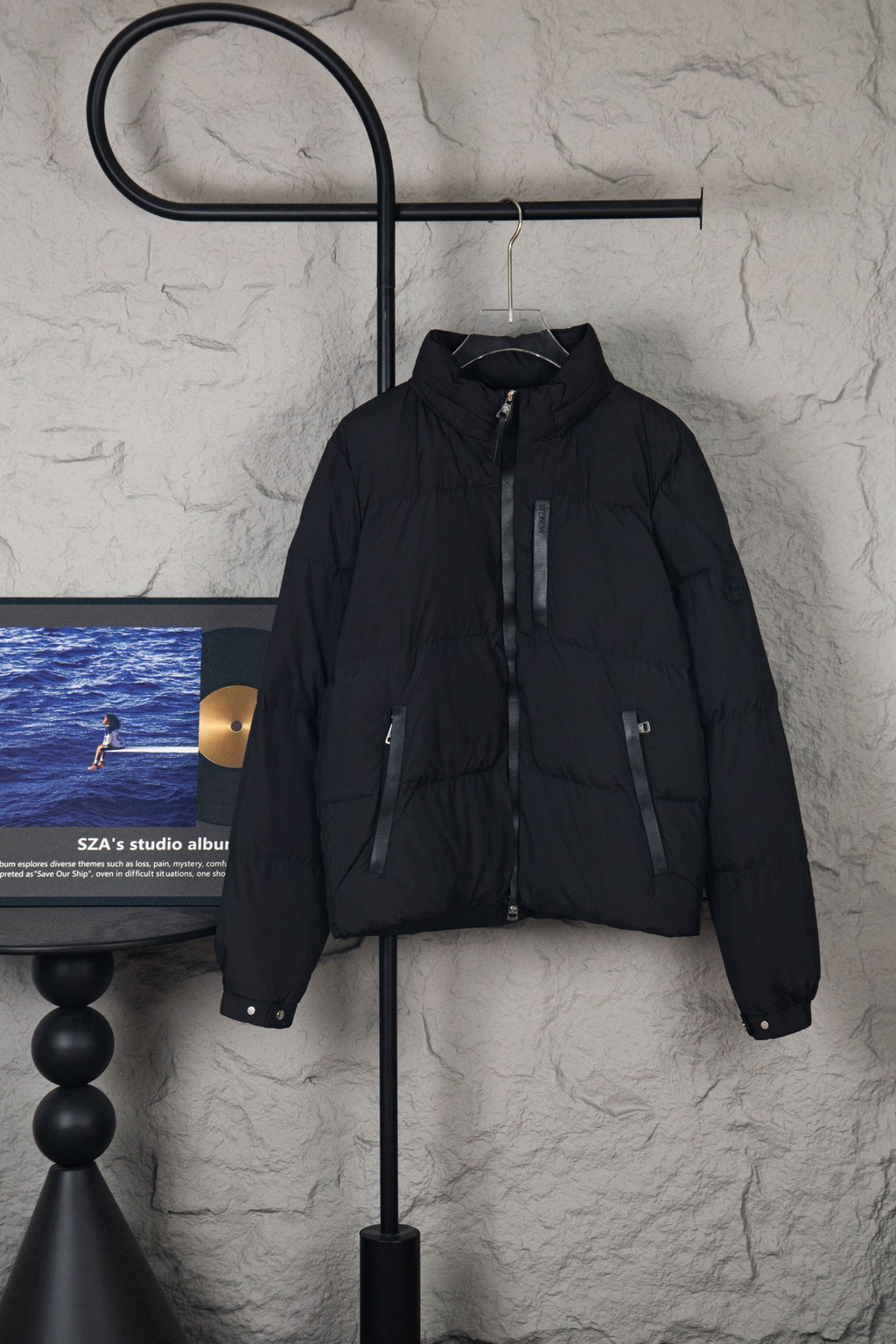 Moncler long black puffer jacket with front zipper and stand collar, hanging on hanger