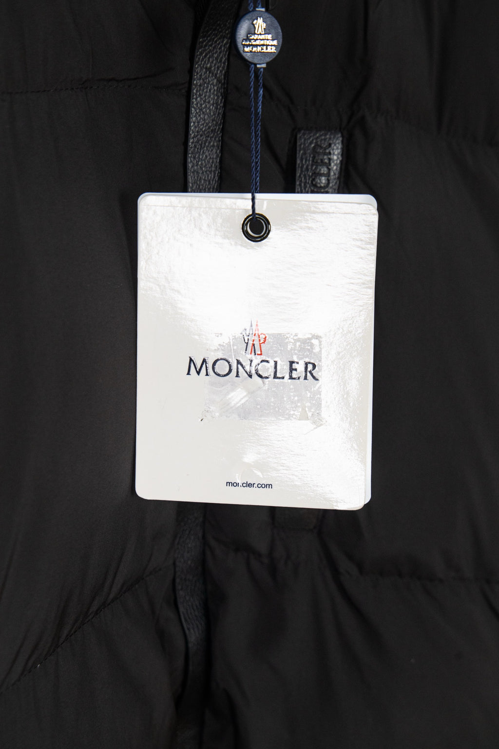 Long black puffer jacket with brand hang tag labeled MONCLER