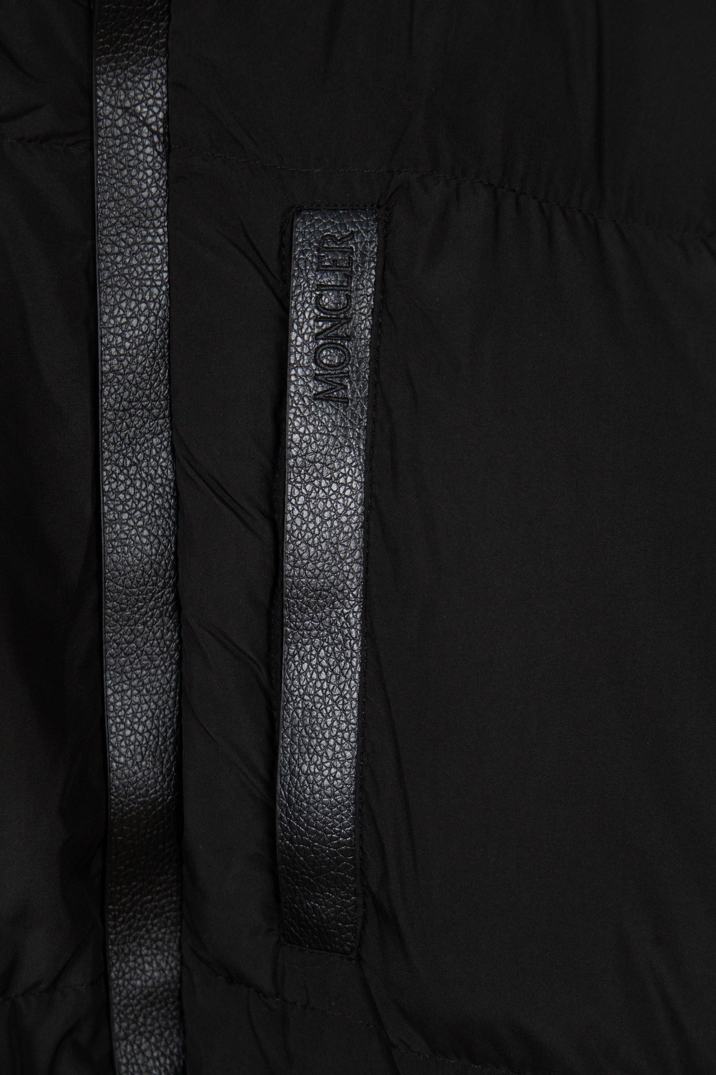 Black puffer jacket center placket with vertical textured label detail