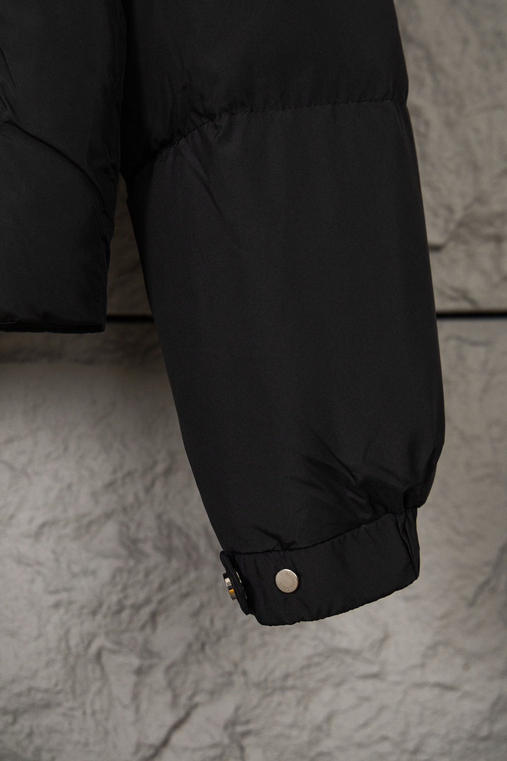 Black puffer jacket lower sleeve with cuff snaps and gathered hem opening