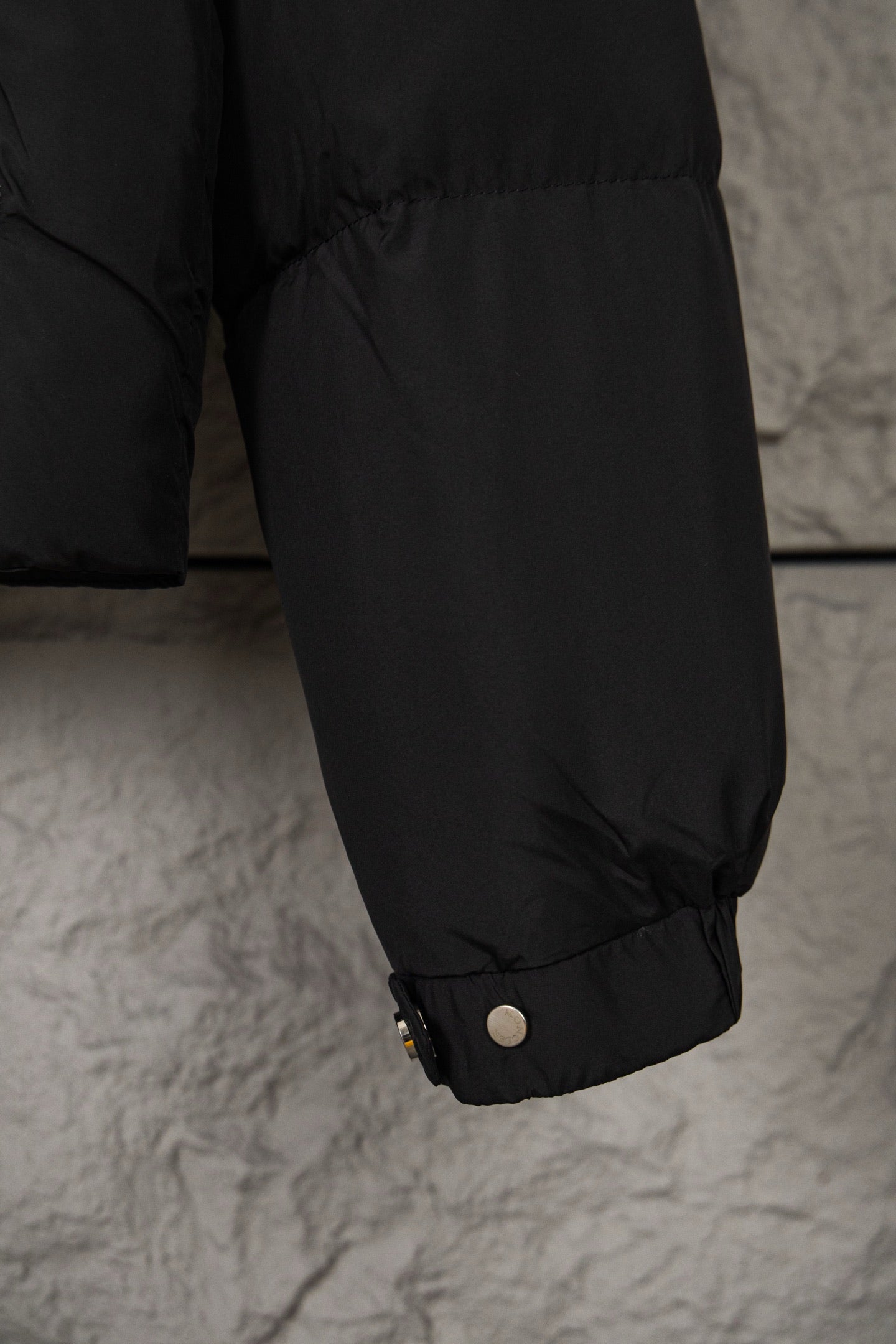 Black puffer jacket lower sleeve with cuff snaps and gathered hem opening