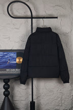 Long black puffer jacket with stand collar and full zipper, back view on hanger