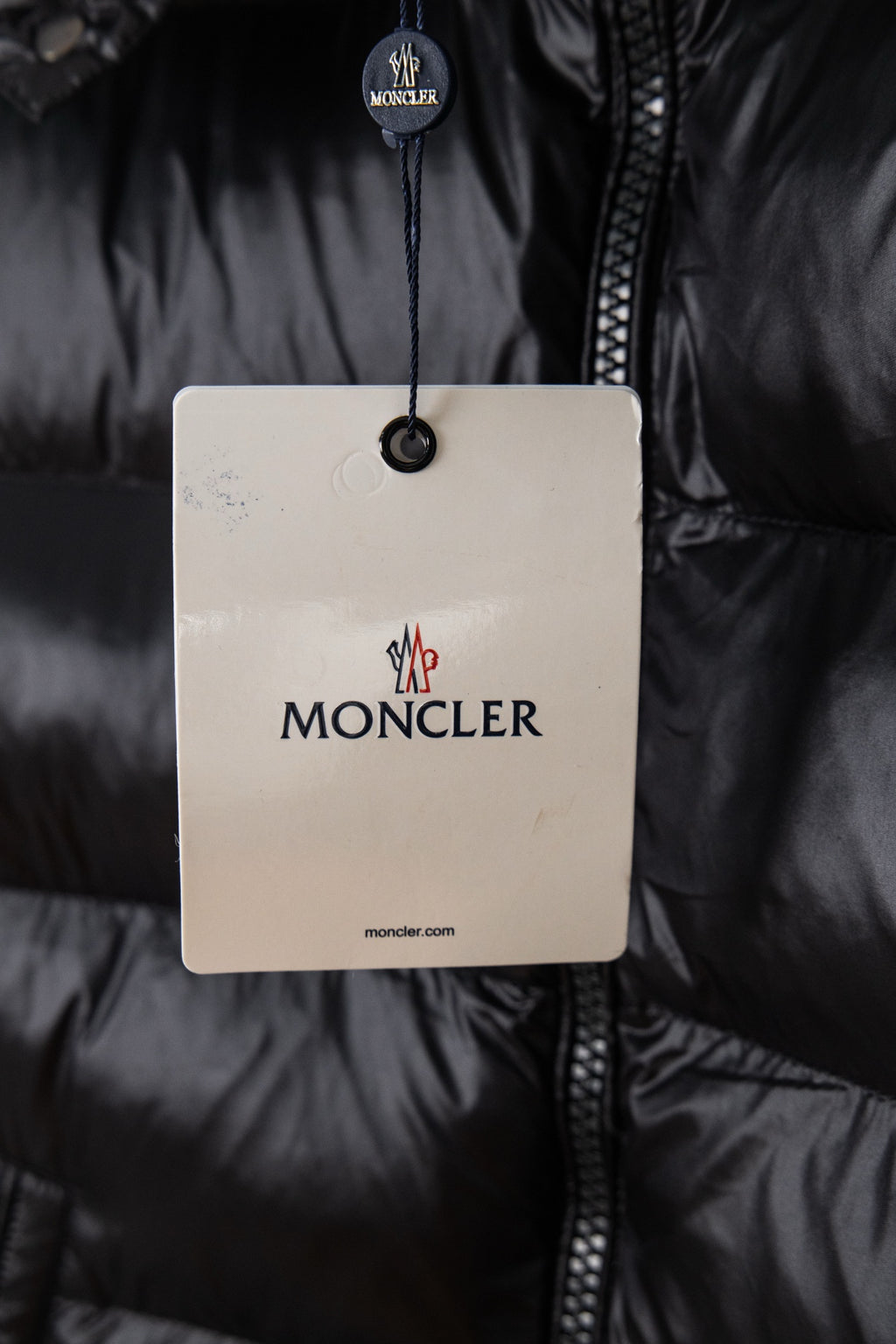 Moncler puffer jacket with hang tag over dark zipper placket
