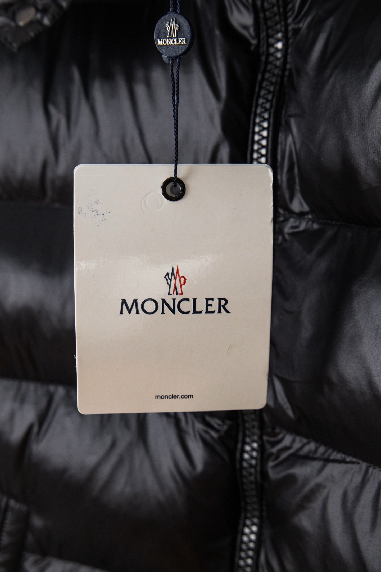 Moncler puffer jacket with hang tag over dark zipper placket