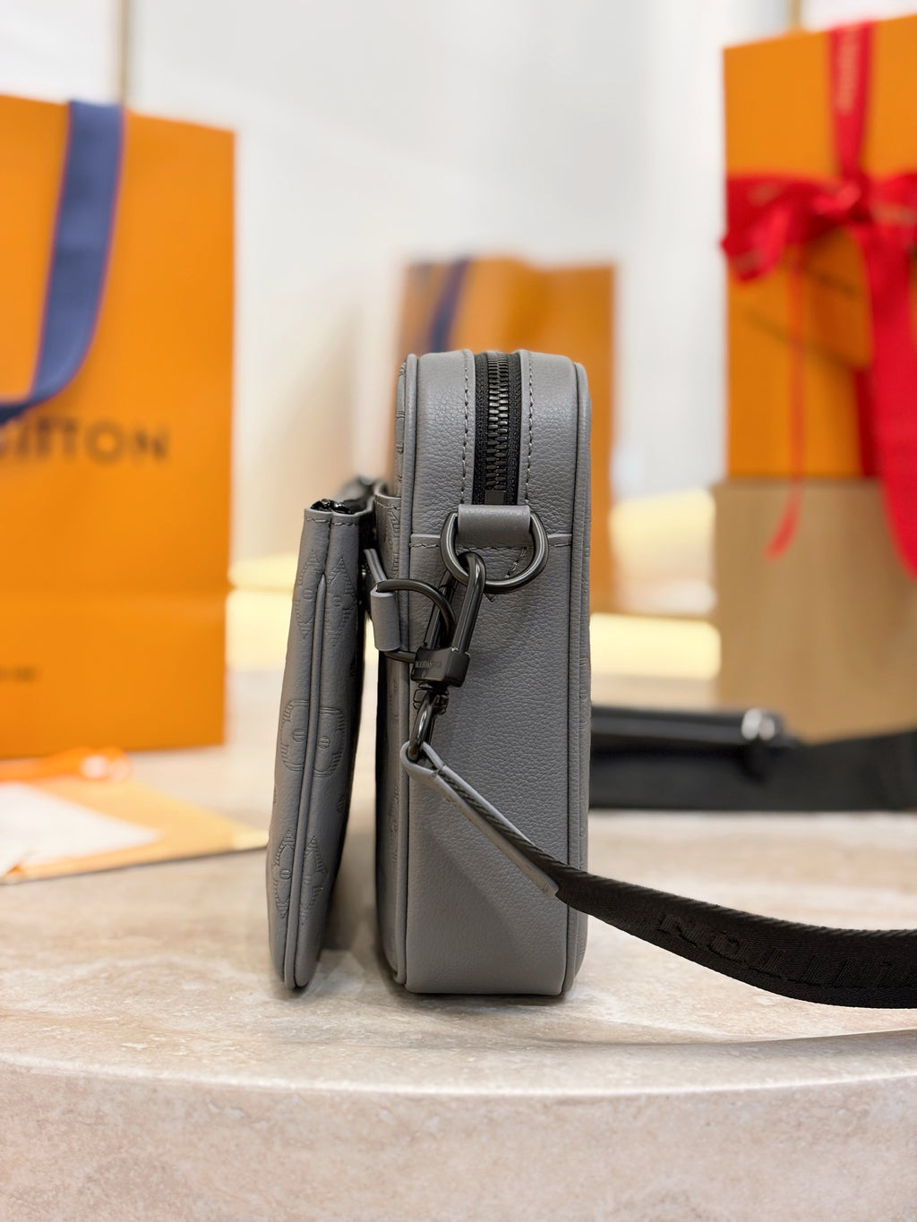Louis Vuitton gray crossbody bag standing view with adjustable strap and side hardware
