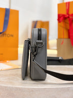 Louis Vuitton gray crossbody bag standing view with adjustable strap and side hardware