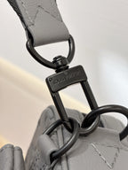 Louis Vuitton gray strap with keyring and logo tag attached to crossbody bag hardware