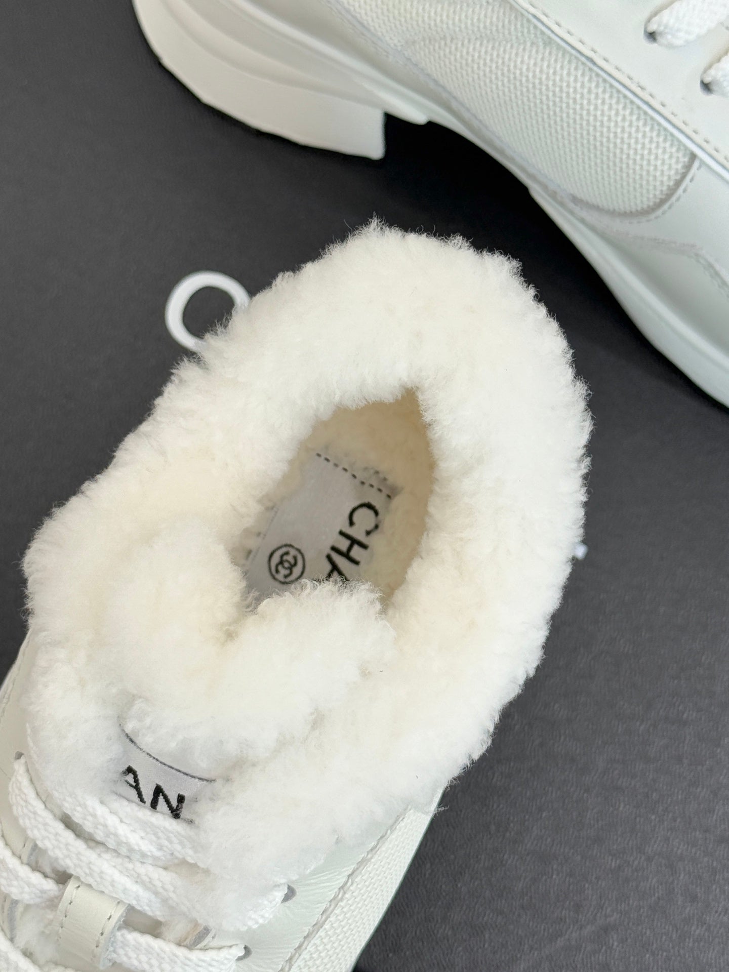 White fur-lined Chanel sneaker with logo detail at the tongue