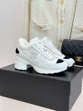 White leather-style sneakers with black side panels and white laces