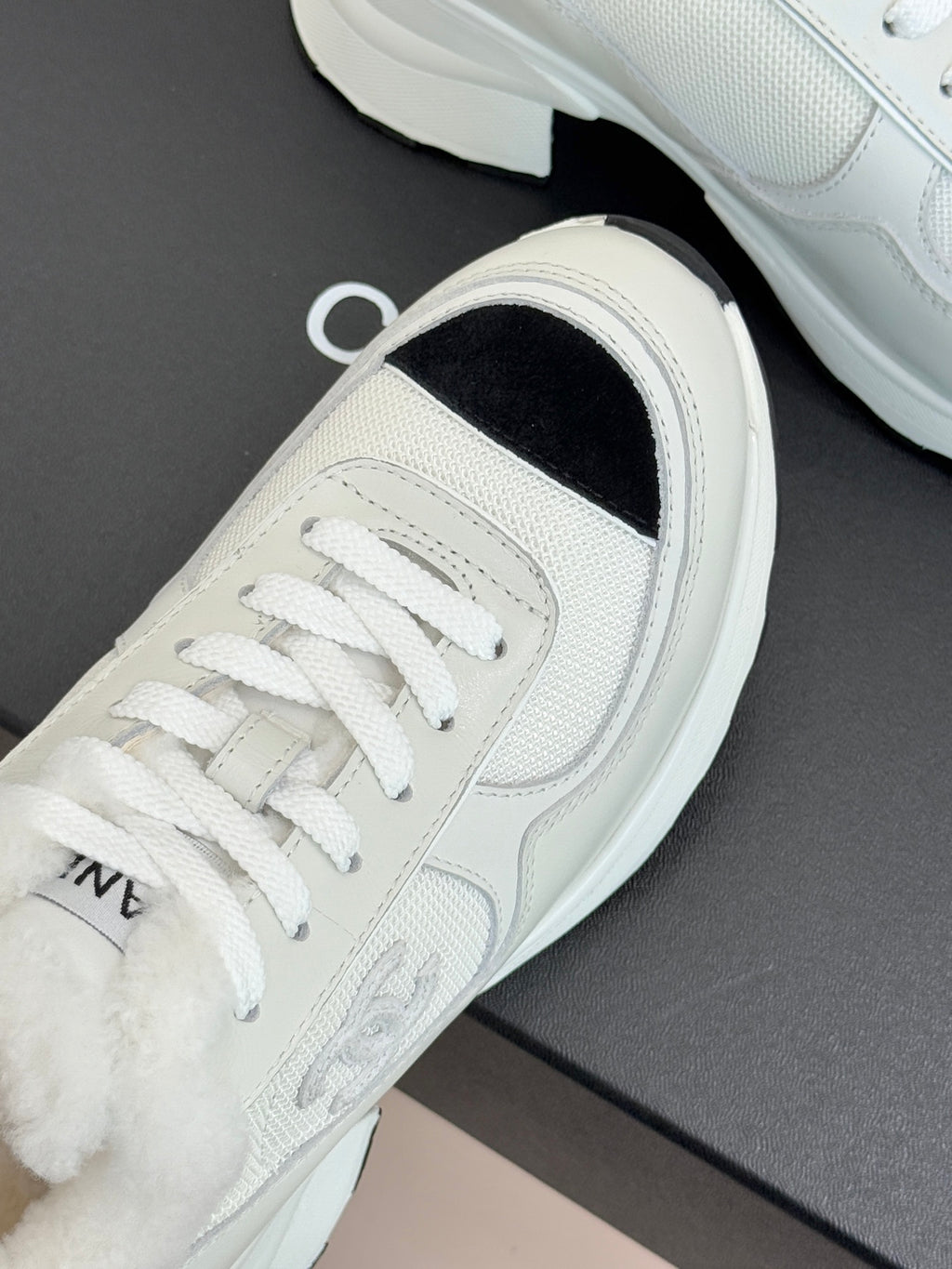 White sneaker showing lace-up front with black interior side panel