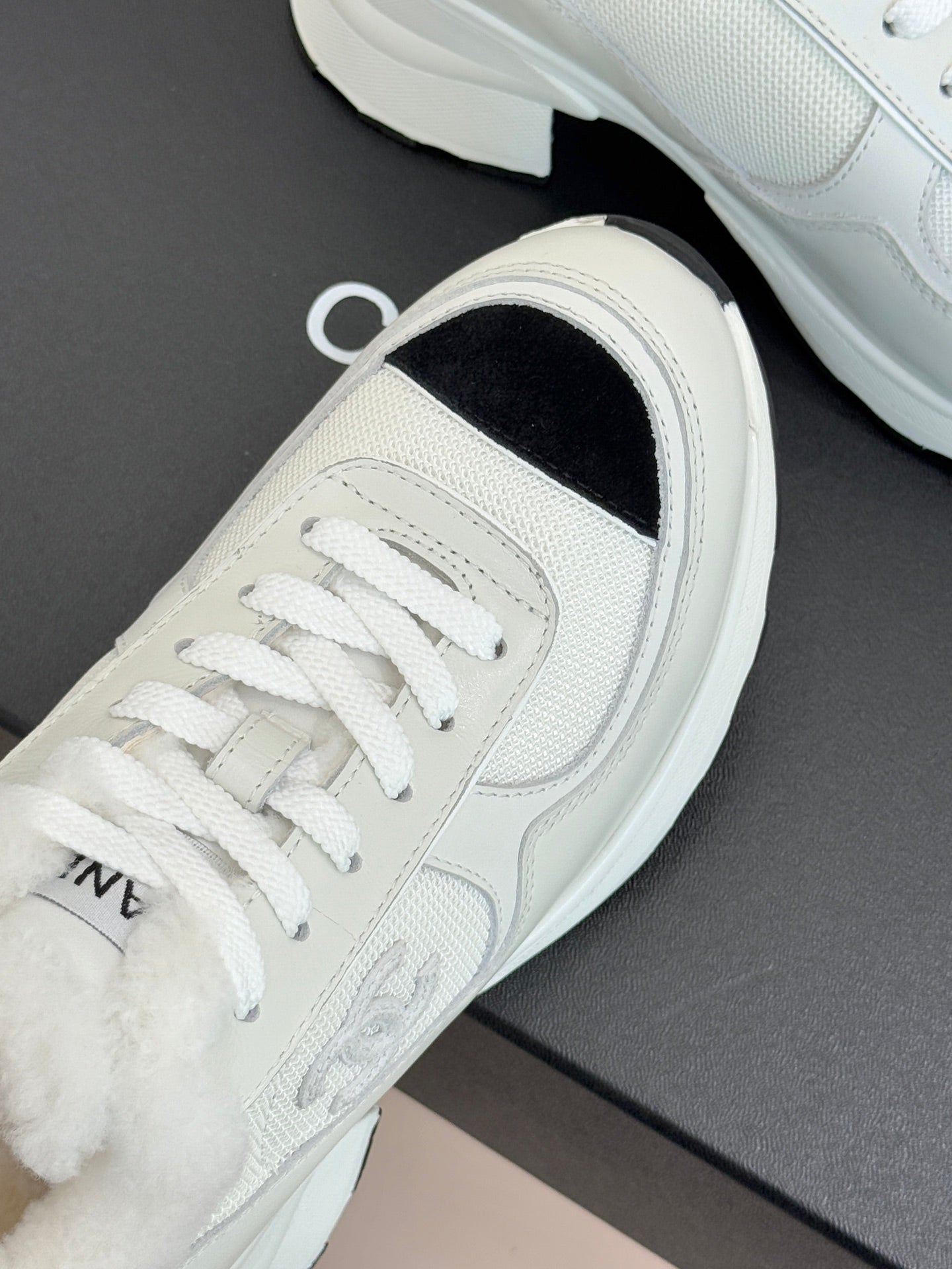 White sneaker showing lace-up front with black interior side panel