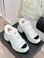 Pair of white sneakers with black side inserts and fur-lined cuffs on display