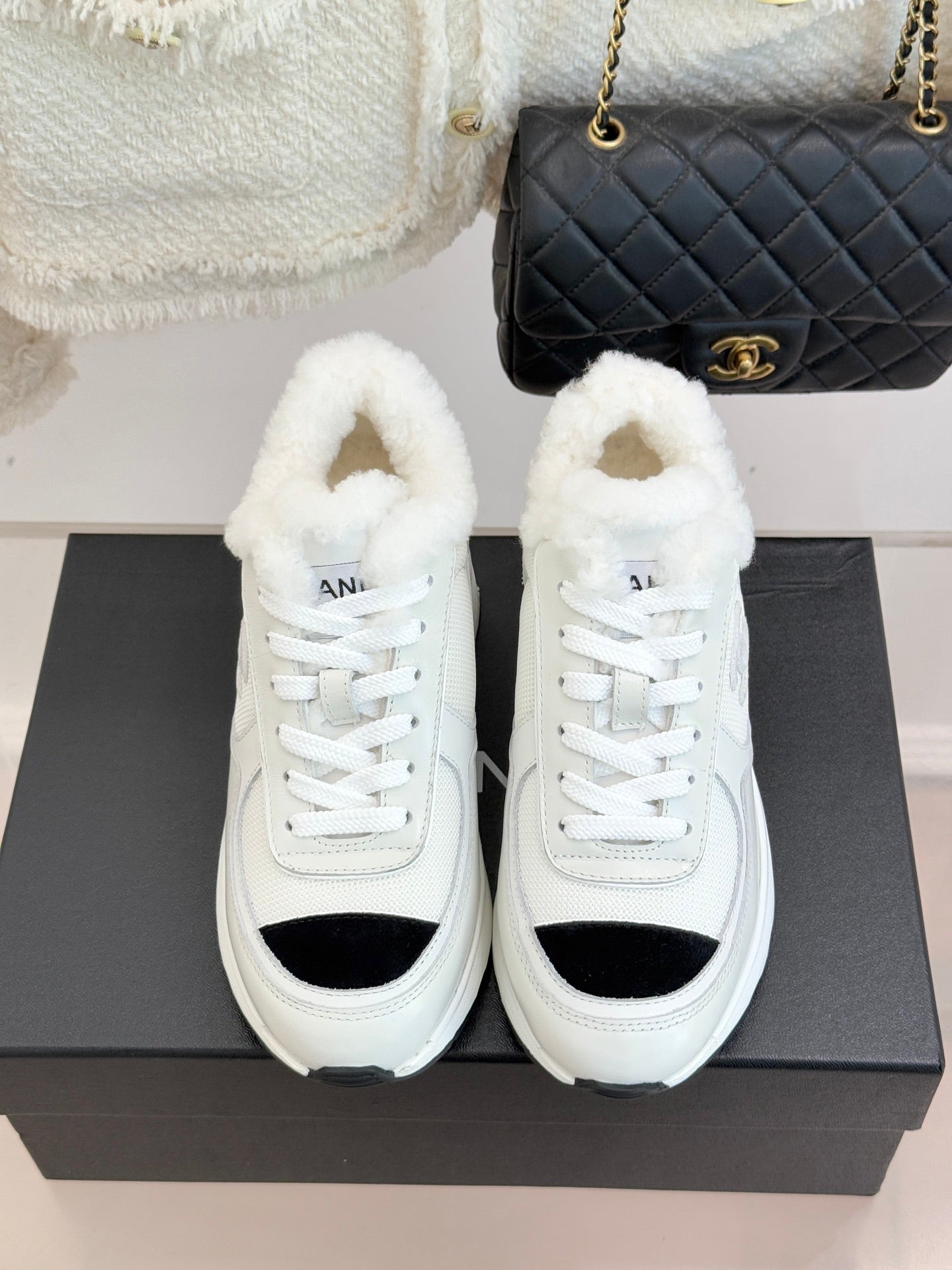 White sneakers with black side inserts, white laces, and plush fur lining