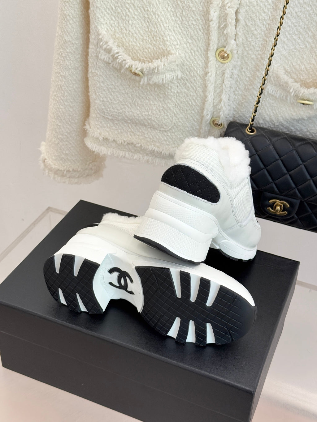 White sneakers with black sole tread and black side inserts on a box