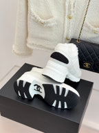 White sneakers with black sole tread and black side inserts on a box