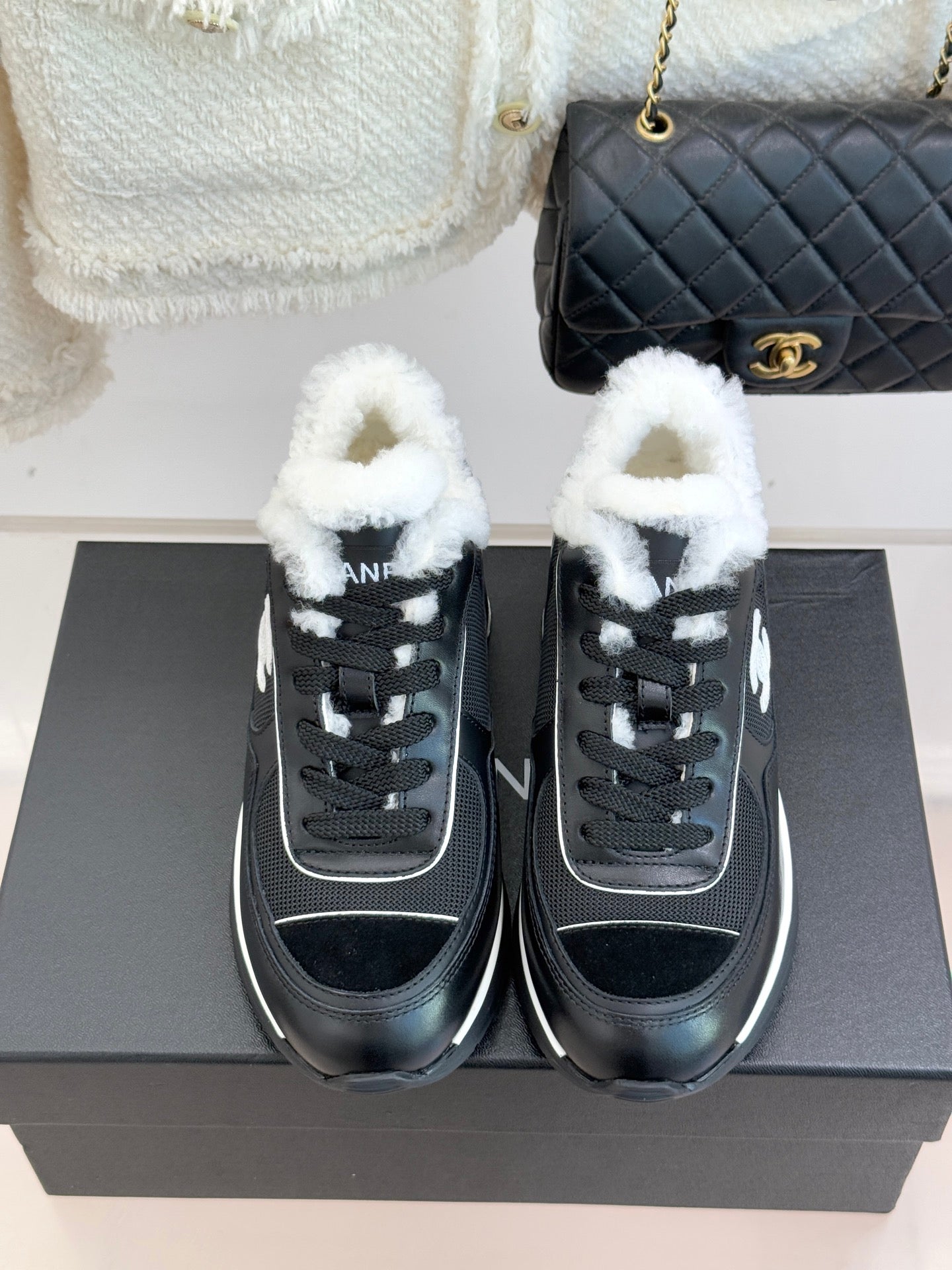 Chanel ladies sneakers, black front view with white logo piping and fur trim