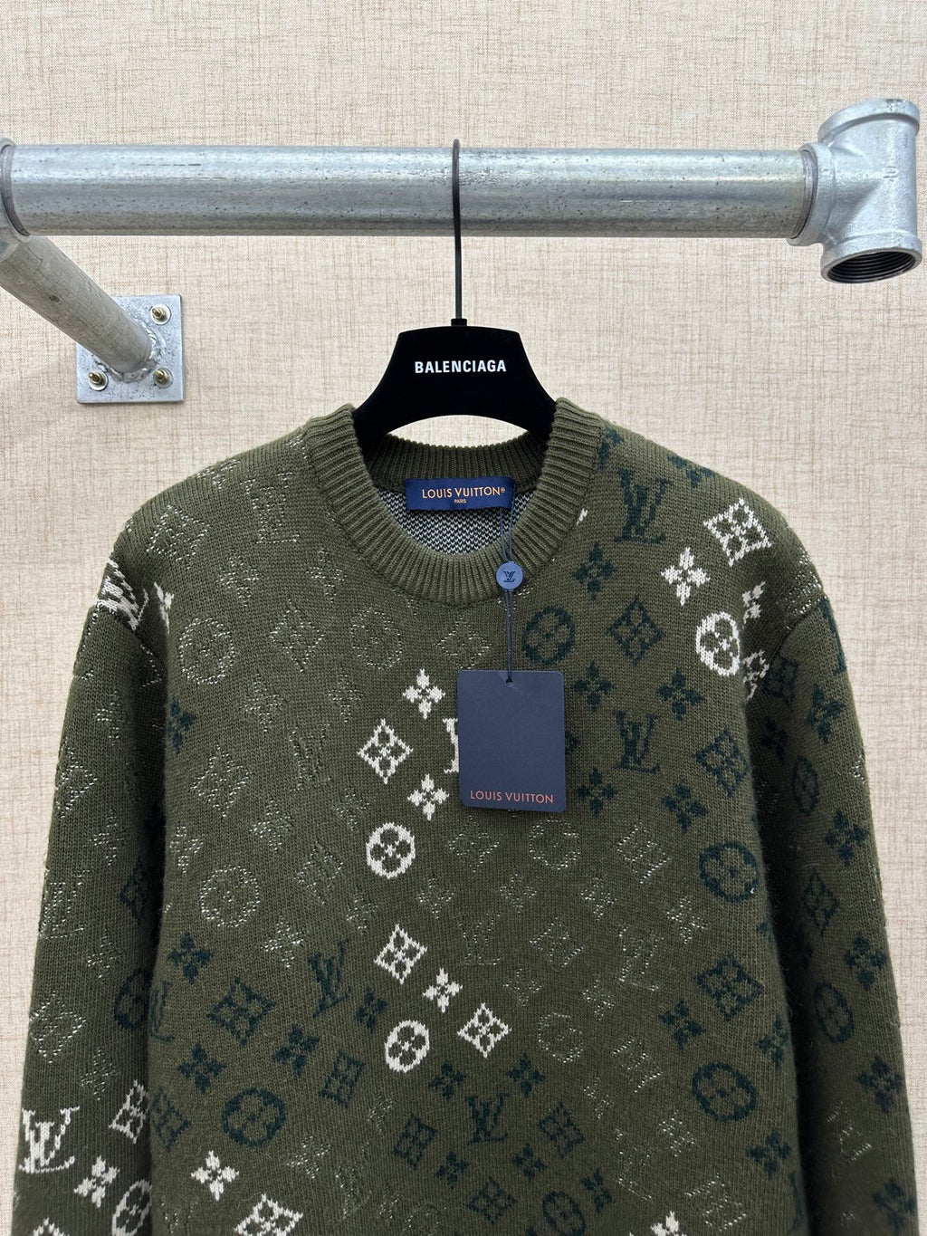 Dark green knit sweater with logo monogram pattern, ribbed crew neck, and buttoned placket