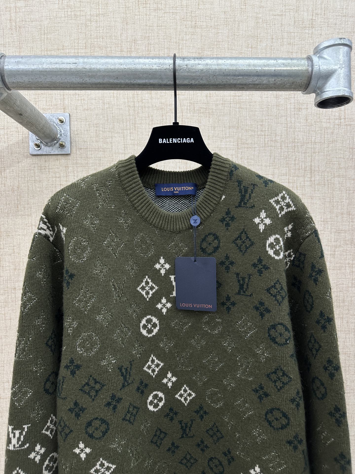 Dark green knit sweater with logo monogram pattern, ribbed crew neck, and buttoned placket