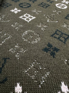 Close-up of dark green knit sweater fabric with dotted white and blue logo pattern