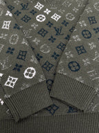 Close-up of dark green knit sweater cuffs with white and blue logo monogram pattern