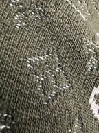 Close-up of dark green knit sweater texture with small white logo elements