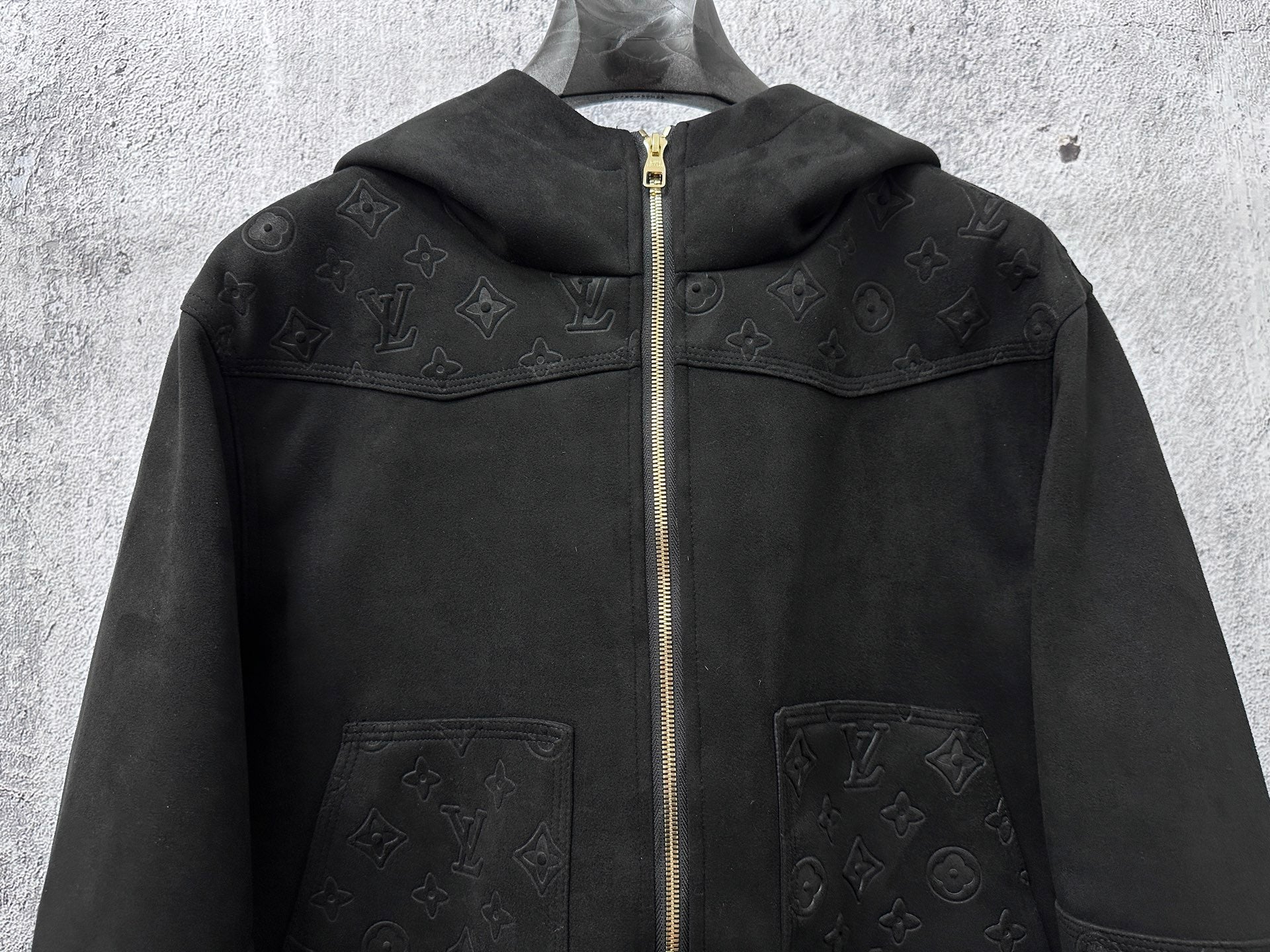 Dark hooded zip jacket front view with monogram panels and two chest pockets