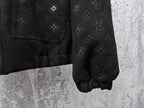 Dark jacket sleeve and hem close-up with embossed monogram pattern and cuff elastic