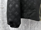 Dark sleeve close-up with embossed monogram icons and partial gold zipper