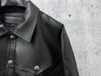 Close-up of dark leather jacket collar and shoulder with decorative snap buttons.
