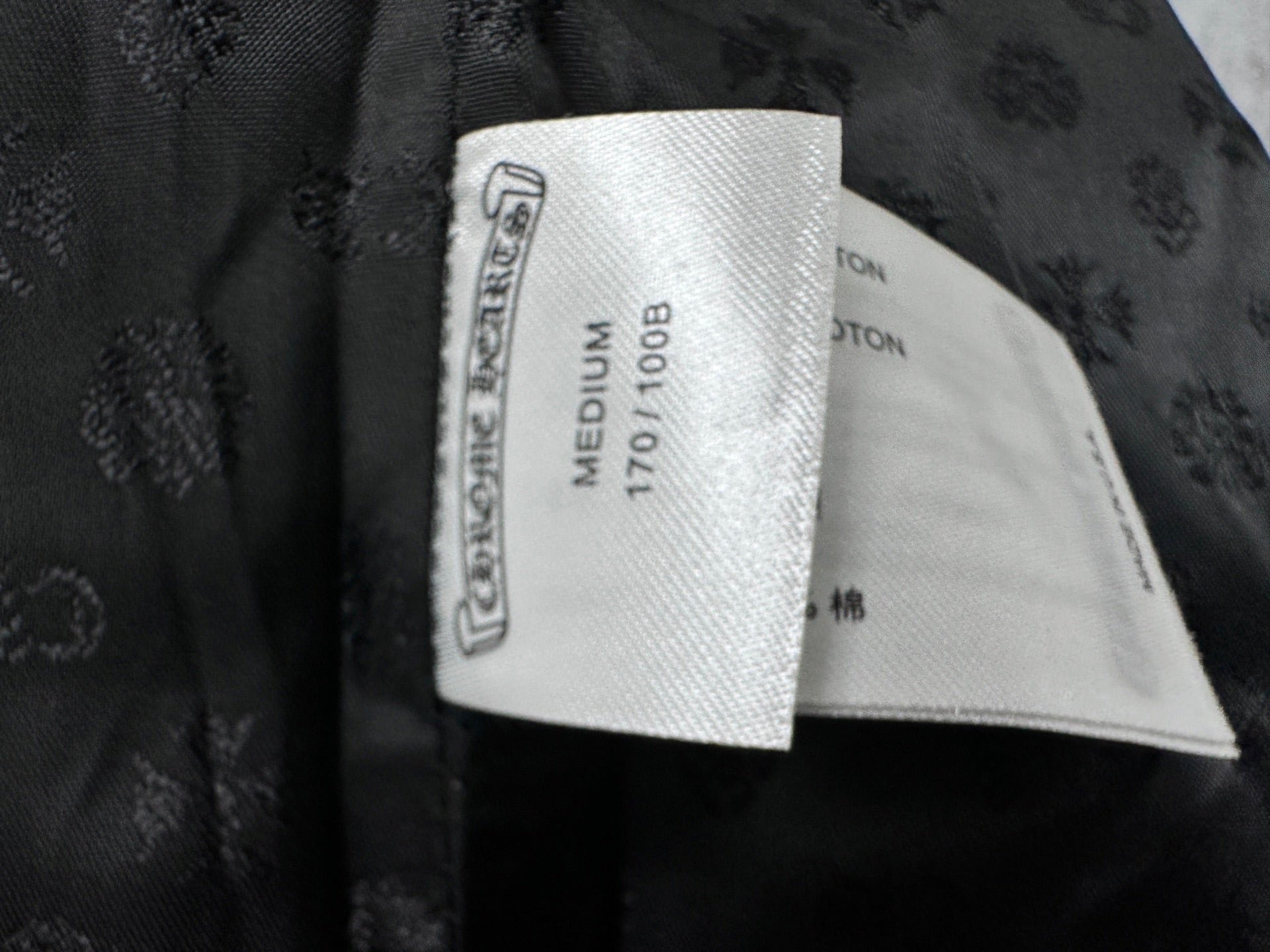 Clothing label inside dark leather jacket, shows size medium and fabric type.