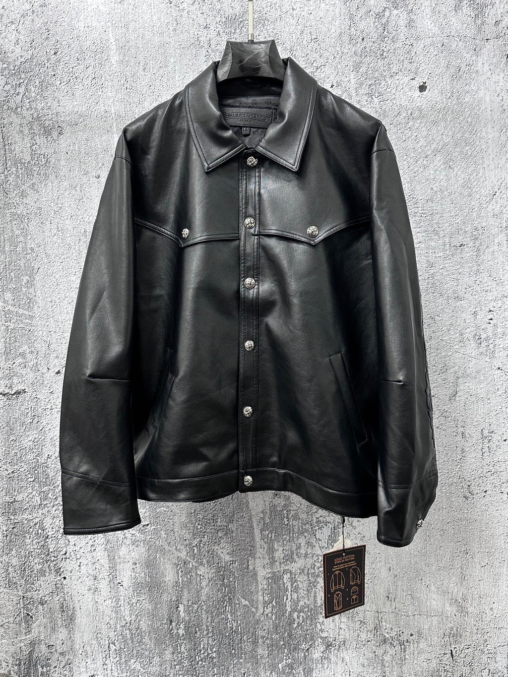Dark leather jacket with spread collar, button front, and chest flap pockets.