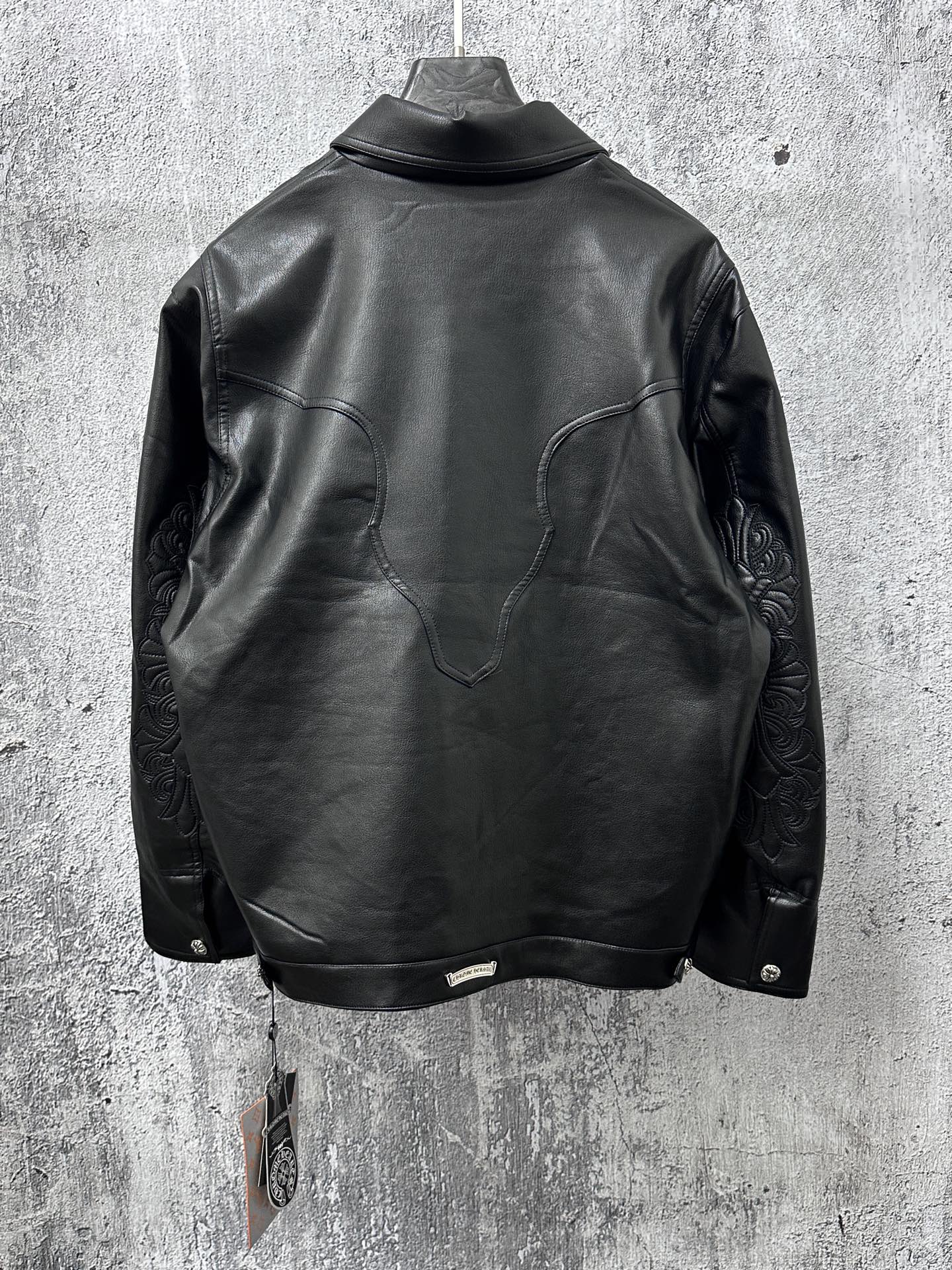 Dark leather jacket back view with curved yoke and long sleeves.
