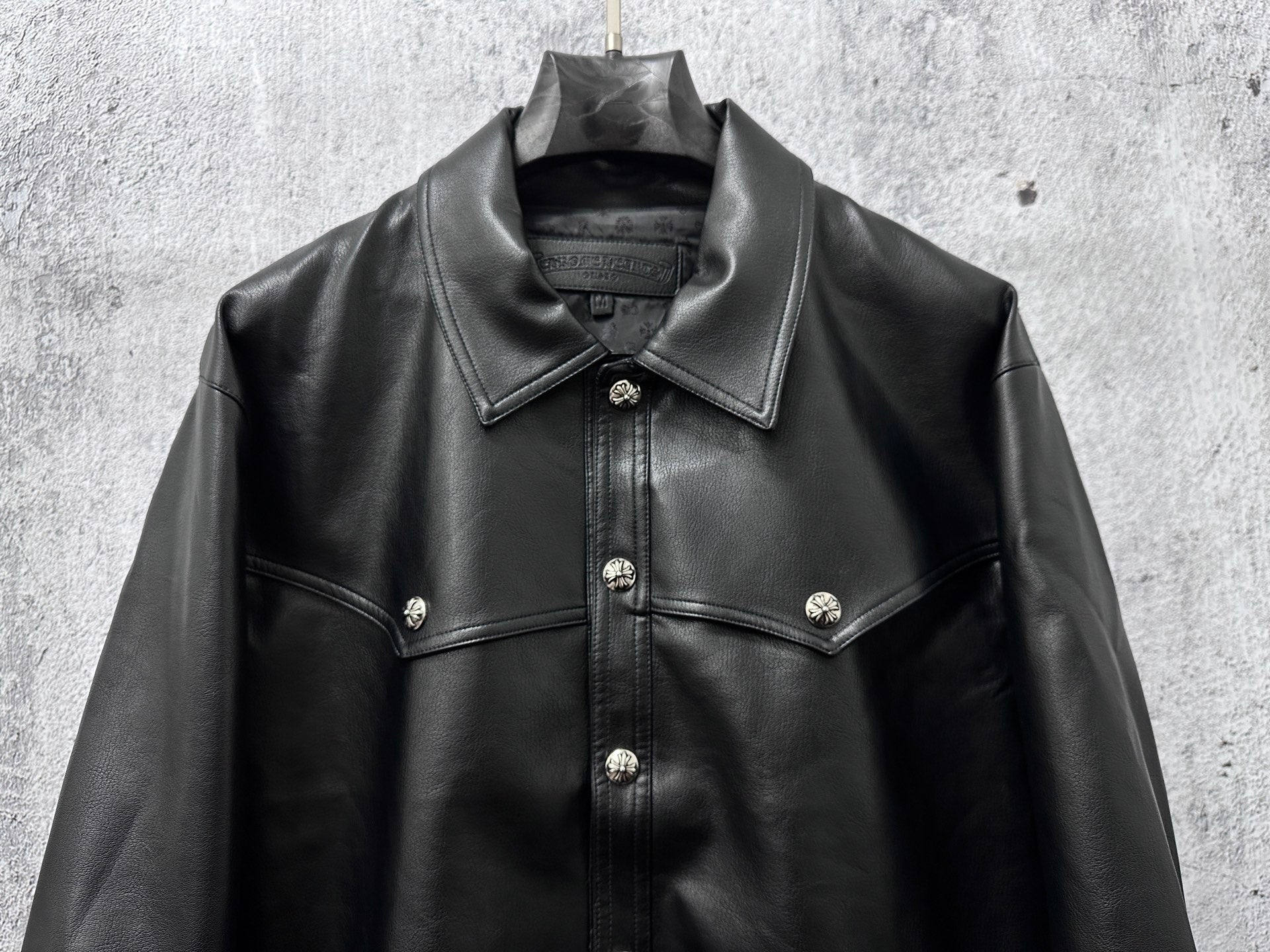 Dark leather jacket front view with button placket and chest yoke details.