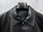 Dark leather jacket neckline with spread collar and central snap placket.