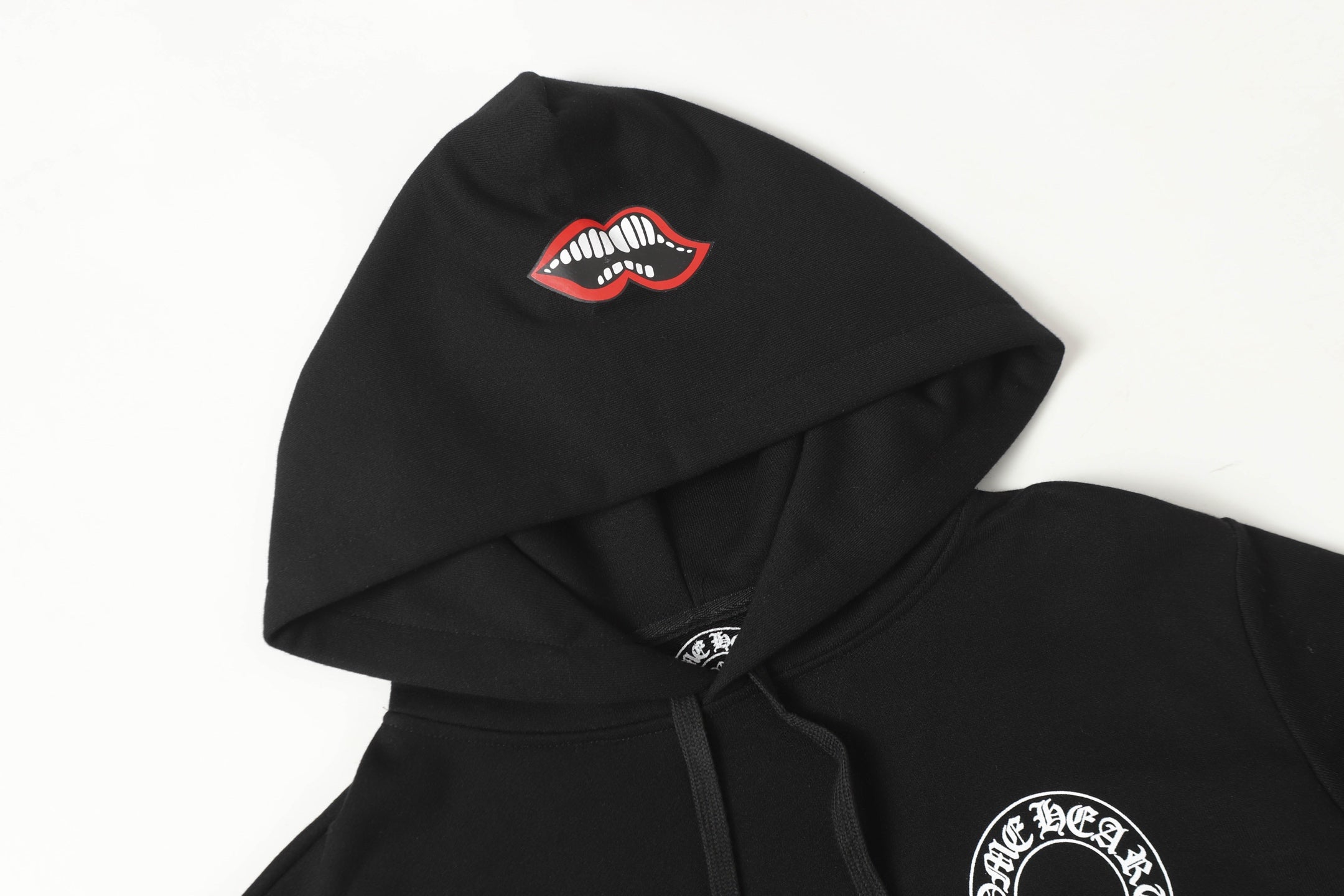 Black hoodie with drawstring hood and small red-and-white lip logo on upper back