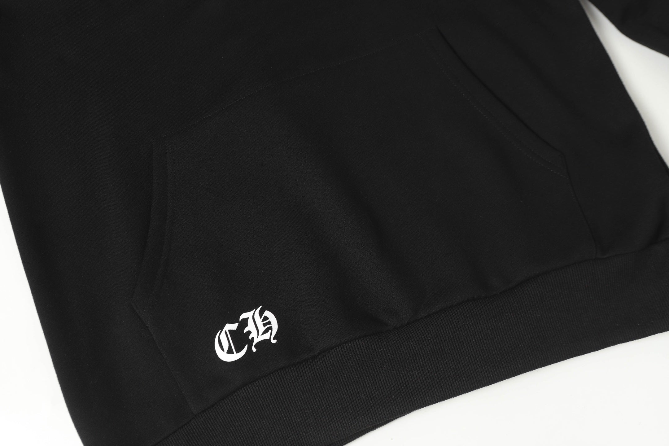 Black hoodie with small white logo on lower front hem