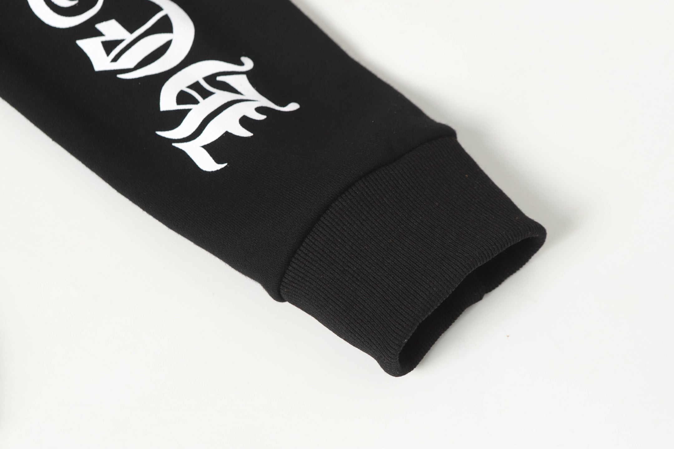 Black long-sleeve hoodie sleeve cuff with white graphic emblem