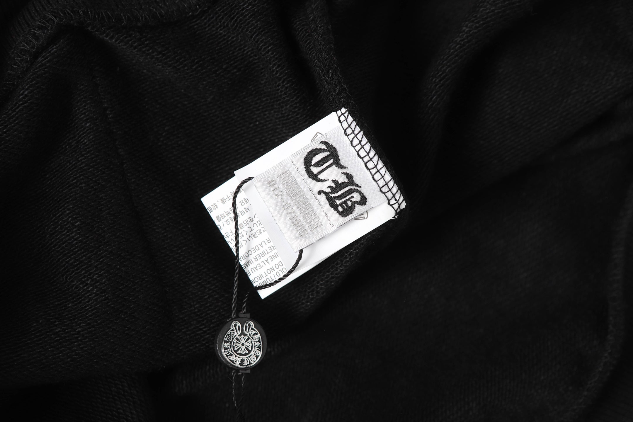 Black hoodie fabric with neck tag and small logo charm