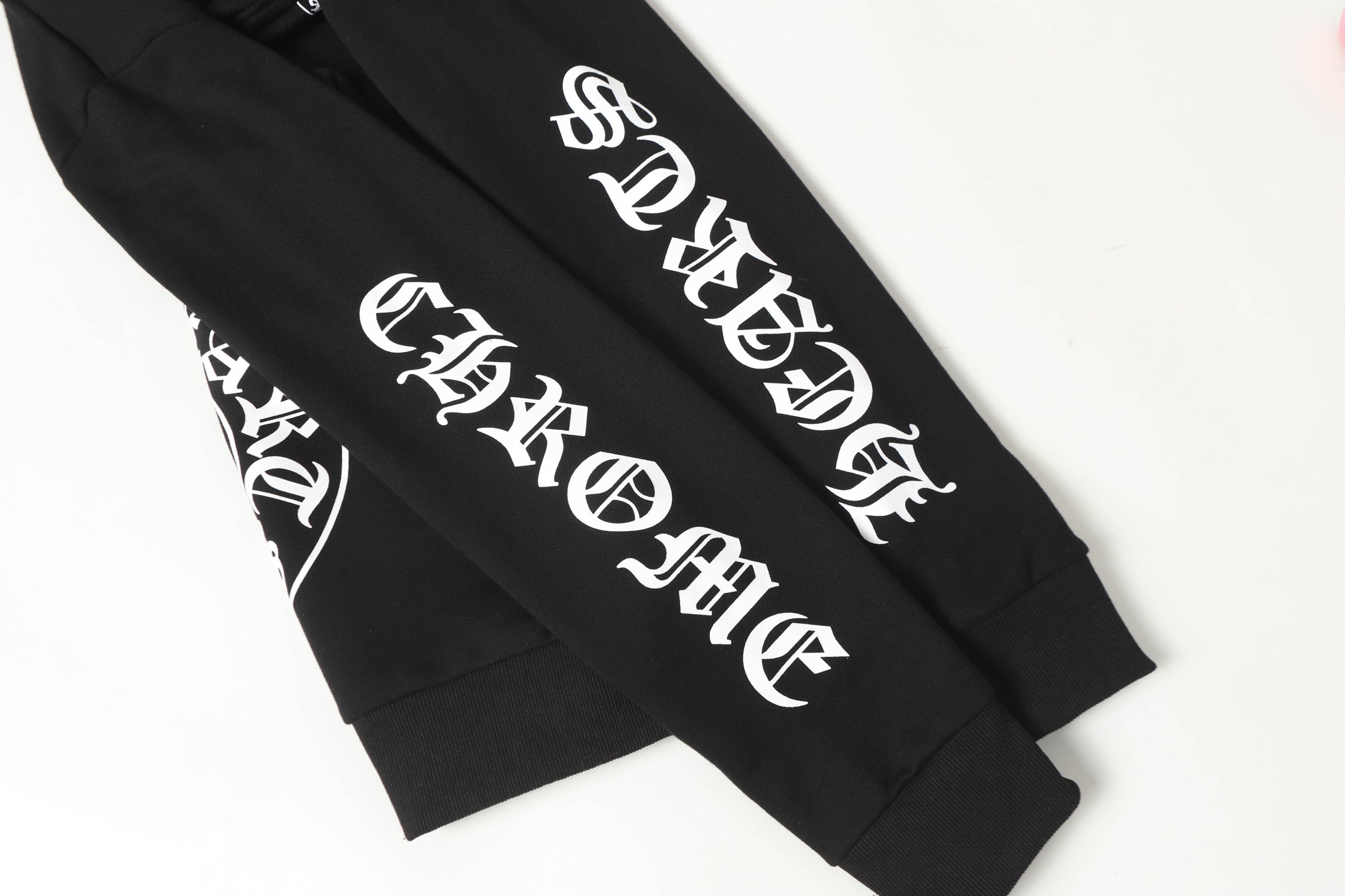Black hoodie sleeve close-up with white stylized logo text