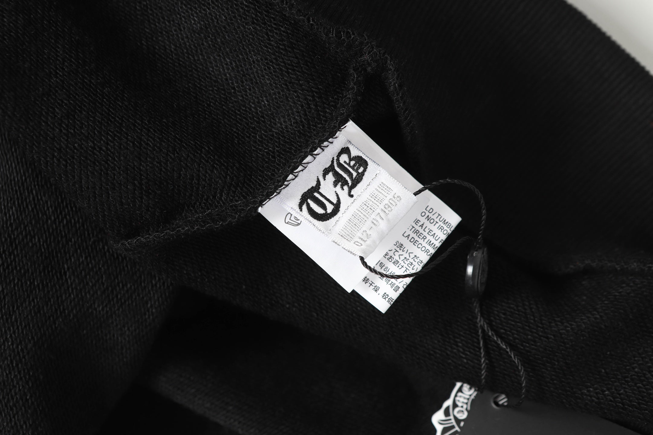 Black hoodie inner neckline label close-up with hanging fabric tag